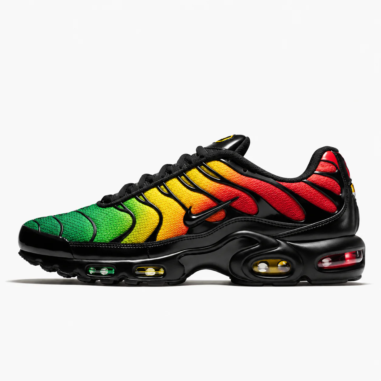 Nike Air Max Plus in black, green, yellow, red, side view of the sneaker on a white background.